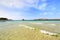 Beautiful sand beach with soft waves against blue sky with clouds - La Pelosa beach with little tower in the background, Sardinia