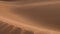 Beautiful sand dunes with wind blowing sand, backlit, in the Sahara desert, Erg Chigaga, Morocco.