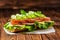 beautiful sandwich with ham, cheese, bacon, radish, lettuce, cucumbers and onions on dark wooden background, close up