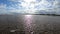 Beautiful sandy beach with bright reflected blue sky.