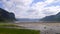 Beautiful sandy beach with high forested mountains against the cloudy sky