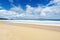 Beautiful sandy beach with wave seafoam clashing on sandy shore turquoise ocean water and blue sky white clouds over sea Natural