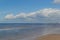 Beautiful sandy shore of the calm northern baltic sea with green stones, blue sky with big white clouds