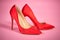 Beautiful, satin red high heels on a pink background