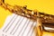 Beautiful saxophone and note sheets on yellow, closeup