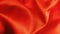 Beautiful scarlet fabric with orange overflow. Shiny silk or satin folded in waves. Closeup. Modern style. Background for a