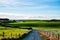 Beautiful scene of agriculture in a rural area at sunset. Green grassland, house, and cloudy sky. I