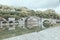 Beautiful scenery of a concrete arch bridge over the calm river surrounded by green trees