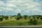 Beautiful scenery of greenery and trees near a highway road under a cloudy blue sky