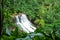 Beautiful scenery of Hoopii Falls in a forest surrounded by greenery in Kauai, Hawaii