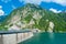 Beautiful scenery of Kurobe Dam on a brisk, with colorful lakeside mountains and crystal clear lake water under blue sunny sky