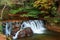 Beautiful scenery of a lovely waterfall tumbling down a rocky stream with colorful autumn foliage