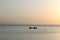 Beautiful sceneryof a small boat with two sailors in the sea during the sunset