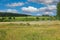 Beautiful scenic dutch rural landscape, green meadows, river Maas, blue summer sky fluffy cumulus clouds - Maasvallei, Limburg,