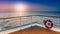 Beautiful scenic sunset view from the deck of a cruise ship with safety railing in the foreground.
