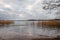 Beautiful scenic tranquil winter landscape of ice, water and reed against a cloudy sky.