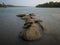 A beautiful scenic view of rocks or boulders in the Sava River against dramatic ominous storm clouds during heavy rain on a rainy