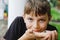 Beautiful school preteen kid boy holding small wild frog. Happy curious child watching and exploring animals in nature.