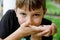 Beautiful school preteen kid boy holding small wild frog. Happy curious child watching and exploring animals in nature.