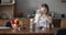 Beautiful schoolgirl pouring milk into a bowl of cornflakes in the kitchen.