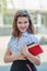 Beautiful schoolgirl teen holds textbooks. Pupil in front of school in schoolyard