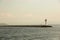 Beautiful seascape with lighthouse. Calm sea and a lighthouse on the pier. Small beacon in the endless sea. Landscape