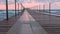 Beautiful seascape with pink sunset, pier and storm waves in evening.