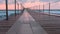 Beautiful seascape with pink sunset, pier and storm waves in evening.