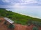 Beautiful seascape with a sandy beach captured from a green hilltop with a wooden bench