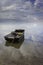 Beautiful seascape with a single boat reflected in the still ocean at sunrise