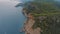 Beautiful seascape. Top view of a rocky shore covered with green trees. Blue water. Aerial drone view.