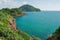 Beautiful seascape view of green hill, rock and long shore with blue sea in background.