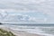 Beautiful seascape with waves, old wooden breakwater, sandy beach and cloudy sky.