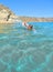 Beautiful seascape with young woman swimming on clear turquoise water on the beach Torre Salsa, Siculiana, Agrigento Sicily, Italy