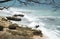 Beautiful seashore with sea wave over rocks and black tree branch silhouette.