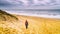 Beautiful seaside landscape - coast of South Holland with girl swimmer who walks along the beach during Nieuwjaarsduik New Years