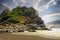 Beautiful secluded black lava sand beach cove, stone rock hill, evening sky clouds - Cobquecura Piedra De La Loberia, Chile,