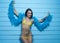 Beautiful seductive brunette woman wearing yellow bikini and blue feather boa smiling and looking into the camera over blue wall