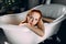 Beautiful seductive young red-haired lady with bare shoulders in bathtub.