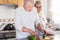 Beautiful senior adult caucasian people couple at home working together in the kitchen - equal rights concept with man and woman