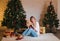 Beautiful senior Caucasian woman holding Christmas gift with happy face. cheerful woman sits in front of a decorated Christmas