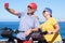 Beautiful senior couple standing on the cliff with bicycles taking a selfie with smartphone. Active retirees enjoying healthy