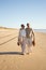 Beautiful senior couple walking on wet sand along empty seashore