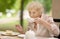 Beautiful senior lady with curly white hair drinking tea in outdoors cafe or restaurant