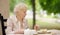 Beautiful senior lady with curly white hair drinking tea in outdoors cafe or restaurant