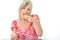 Beautiful senior woman in pink dress eating yellow and pink macaroon