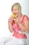 Beautiful senior woman smiling in pink suit eating yellow macaroon