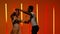 A beautiful sensual couple perform passionate dance steps of Hispanics against a bright red orange neon background. A