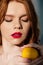 Beautiful sensual redhead girl with red lips posing with lemon.