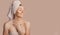 Beautiful sensual young girl with clean skin on a beige background with a mockup. Topless woman in a towel. The concept of spa